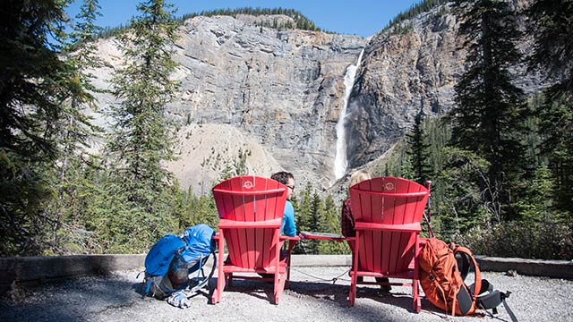 two visitors sitting on red chairs 