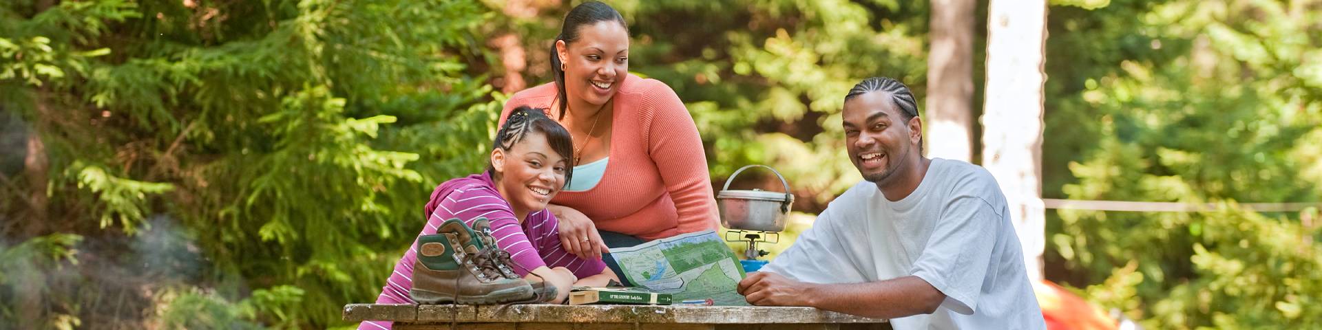 A family sitting on a picnic table near their tent