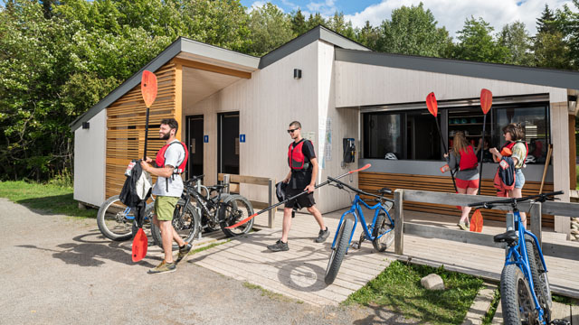 Des visiteurs au kiosque de location d'équipement Ryans avec des rames de kayak.