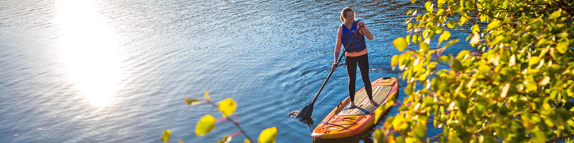 Une visiteuse fait de la planche à pagaie sur une rivière en automne.