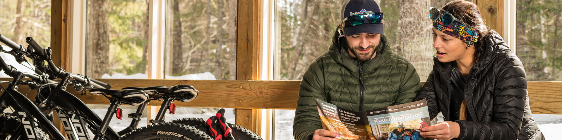 A couple sitting inside a shelter, looking at a visitor guide.