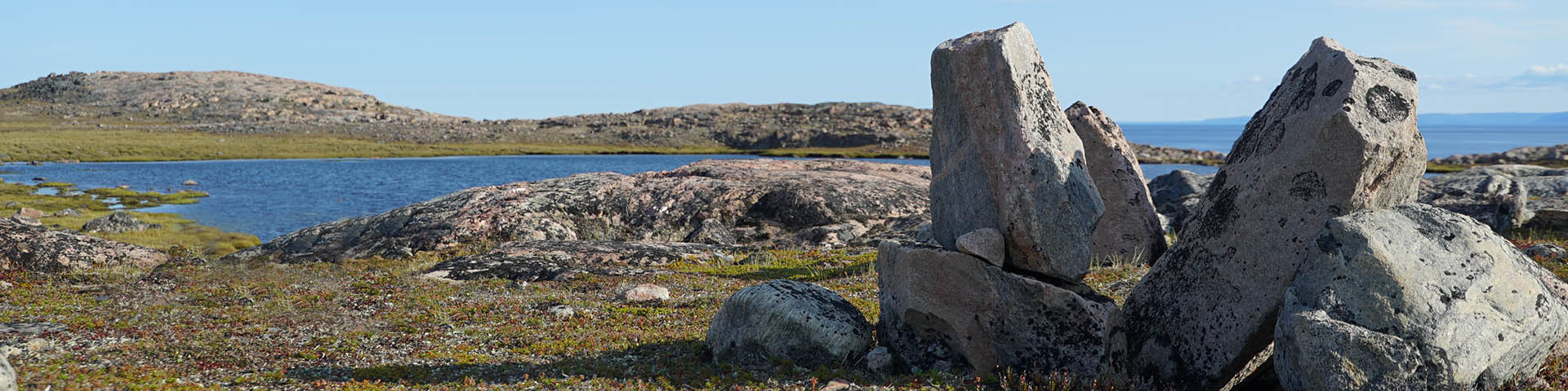 Une structure rocheuse entourée d'un paysage de toundra. 