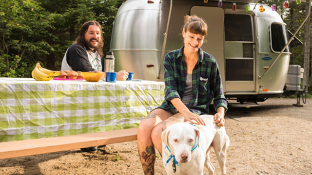 A couple outside of a trailer with their dog.