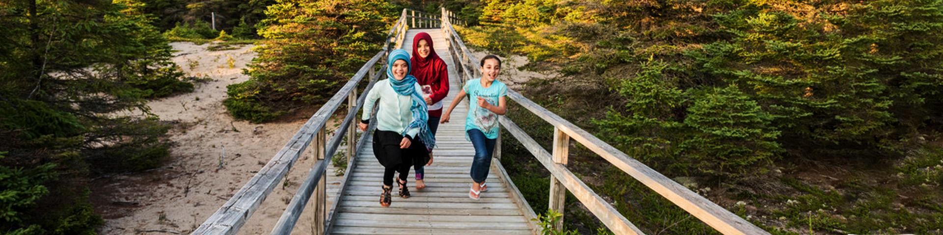 A group of children running down a boardwalk.