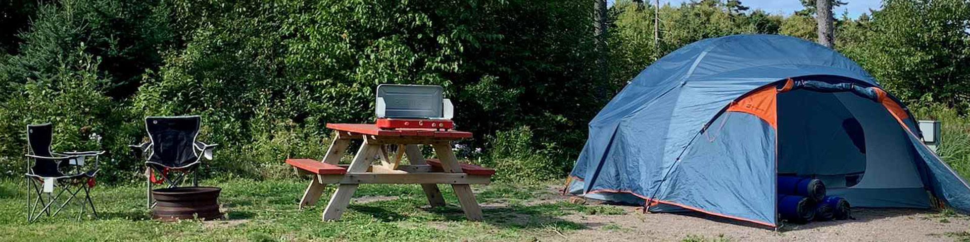 Tente, table de pique-nique et chaises dans un camping. 