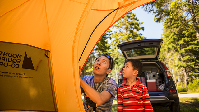 A young child and an adult work together to put a tent up.