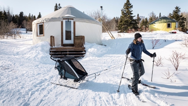 Une skieuse trainant un baby glider quitte le site d'une yourte. 