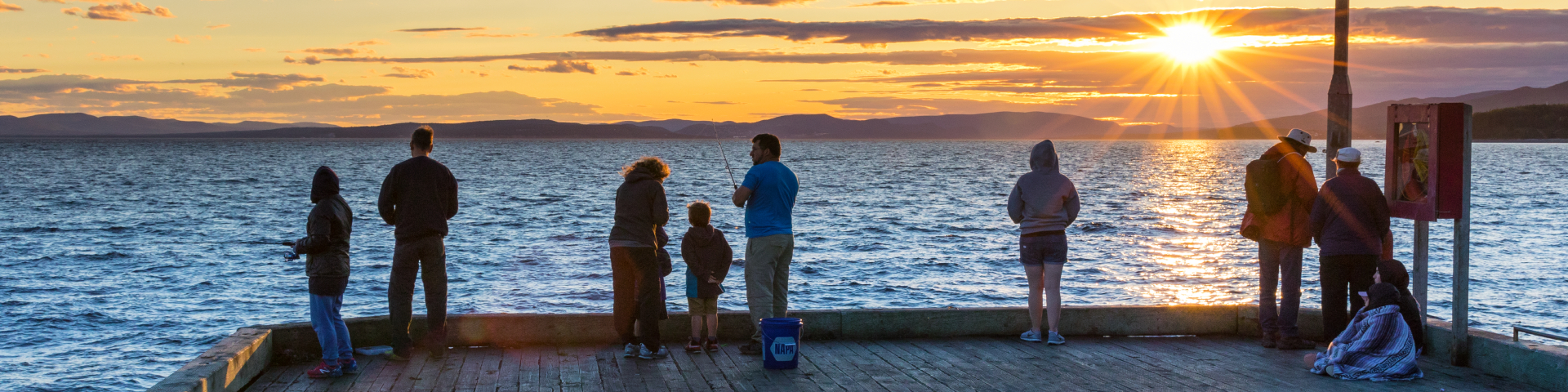 Group of fishers at Grande-Grave wharf at sunset. 