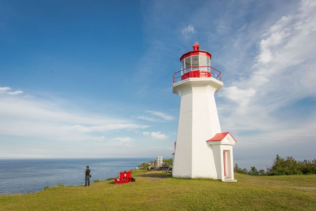 A visitor looks out over the sea from the foot of a lighthouse. 