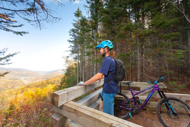 Un amateur de vélo de montagne prend une pause à un belvédère en automne. 