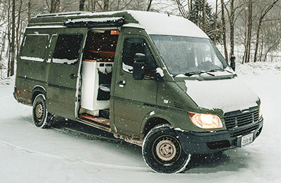 A vanlife camper is parked in the snow.