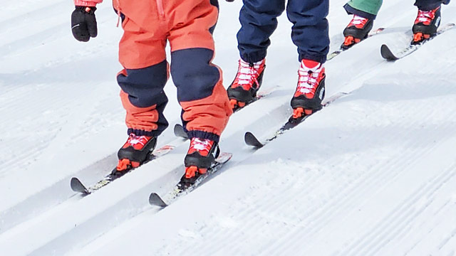 Trois enfants pratiquent le ski de fond.