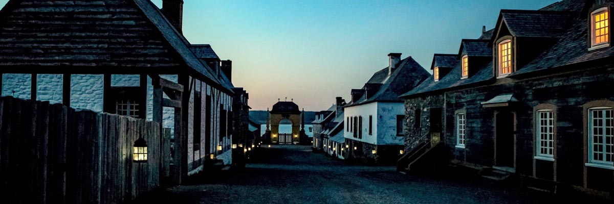 La basse-ville de la forteresse de Louisbourg est éclairée à la lanterne lors d’une soirée au ciel dégagé.