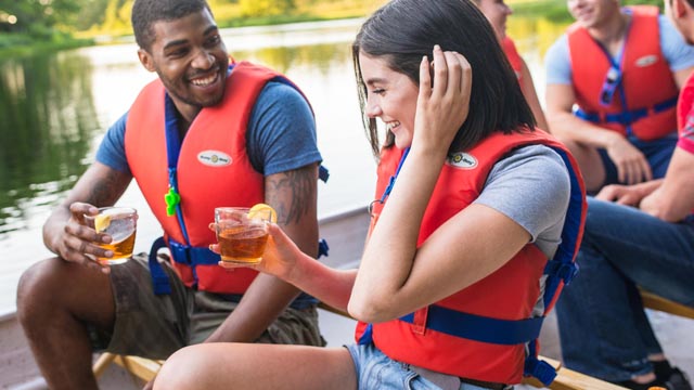 Visitors on a 10-person voyageur canoe enjoying a glass of iced tea on a sunny afternoon during the Mersey Stillwater Paddle tour. 