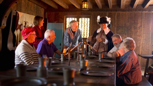 A guide interpreter in period costume speaks with visitors.