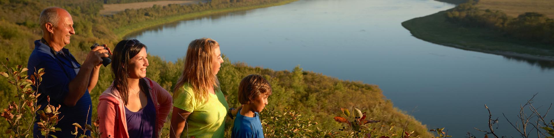 Four visitors looking at a sunset landscape near the river at Batoche National Historic Site.