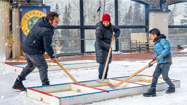 Une famille joue au hockey en déplaçant la rondelle dans une petite structure en bois.