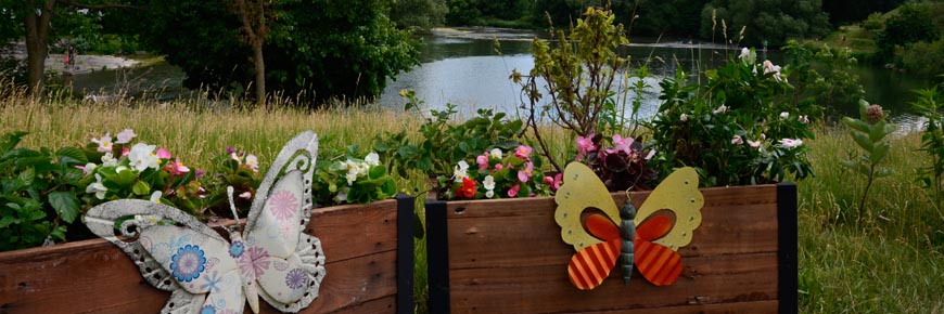 Des fleurs dans un jardin surélevé en bois avec des décorations en forme de papillon.