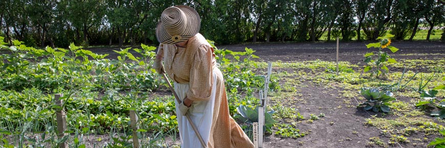 Une guide en costume d'époque travaille dans le jardin du lieu historique national du Homestead-Motherwell. 